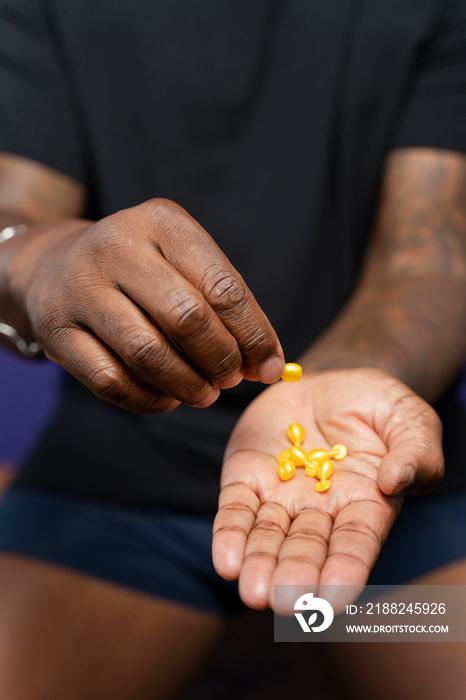 Close-up of man holding yellow capsules in hands