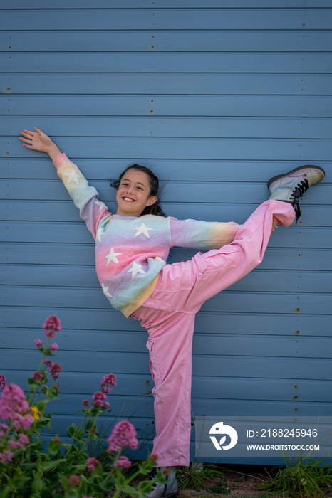 Smiling girl (8-9) standing on one leg outdoors