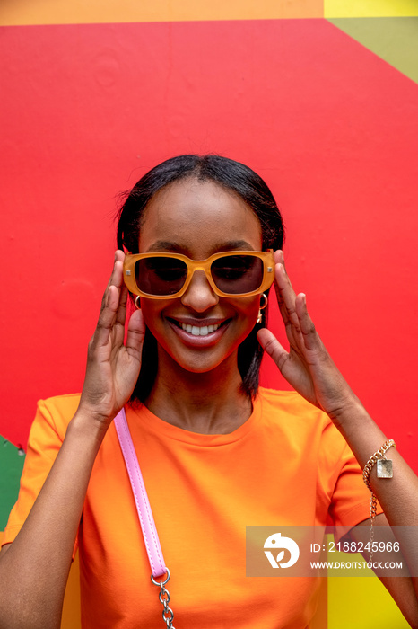 Portrait of smiling young woman in orange sunglasses