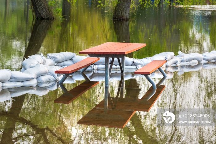 Plastic flood protection sandbags stacked into a temporary wall around the picnic table to protect park from flood