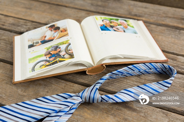 Photo album with necktie on wooden table