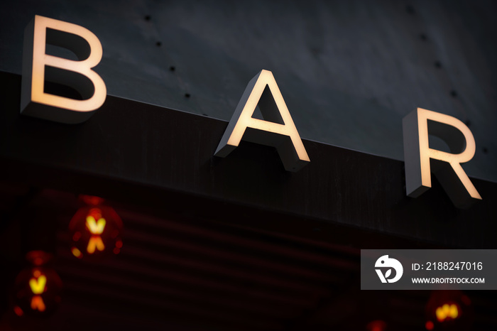 Sign with the letters BAR and red lights in defocus in background