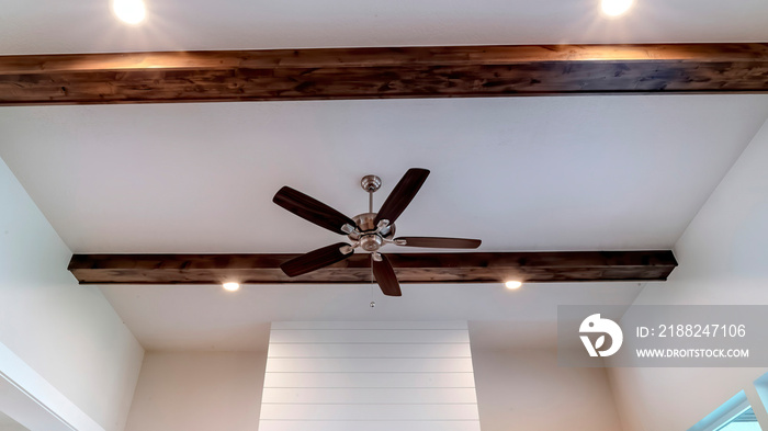 Panorama crop Ceiling fan with lights between decorative wood beams inside living room of home