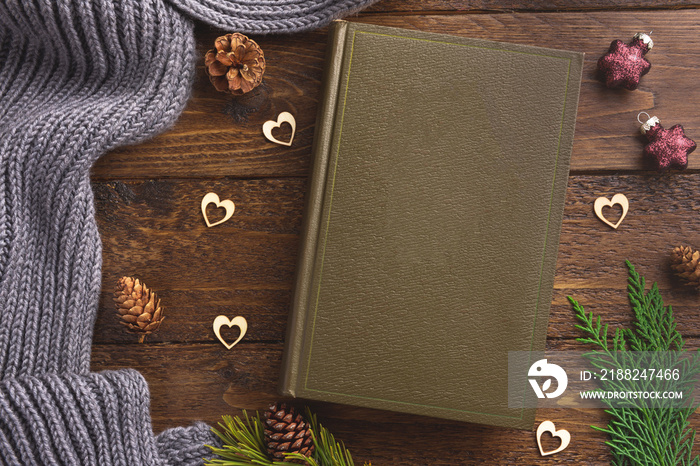 Winter, cozy composition. Warm plaid, book and christmas decoration, on wooden background. Flat lay, top view, copy space.