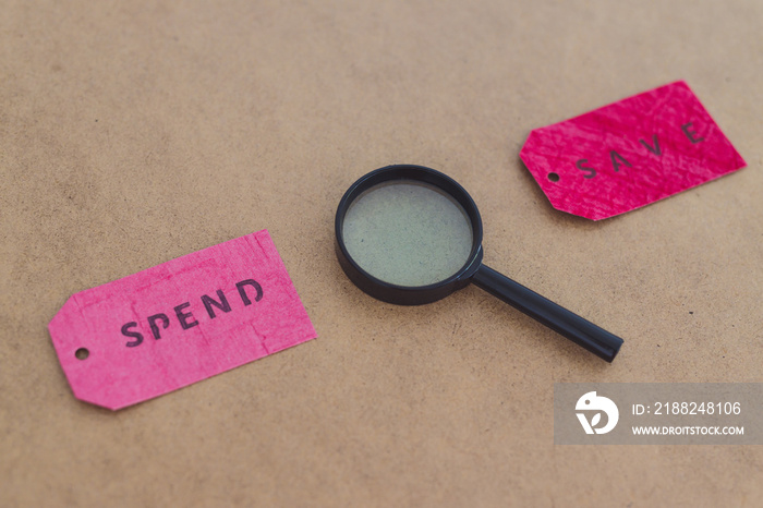 Spend vs Save texts on price tags with magnifying glass, budgeting concept