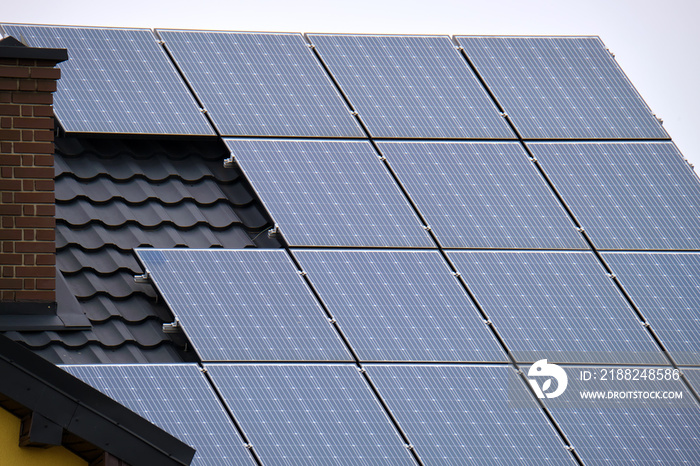 Residential house with rooftop covered with solar photovoltaic panels for producing of clean ecological electrical energy in suburban rural area. Concept of autonomous home