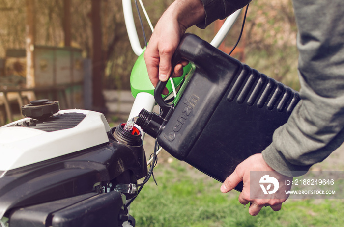 A man pours gasoline from the canister into the cultivator tank