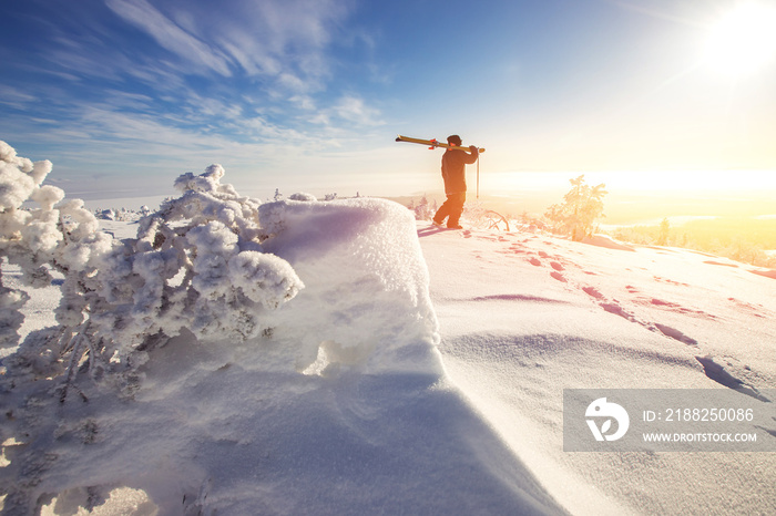 Man skier stands with ski on mountain top on sunrise backdrop. Fresh snow freeride