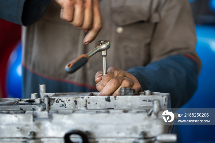 An auto mechanic repairs an internal combustion engine