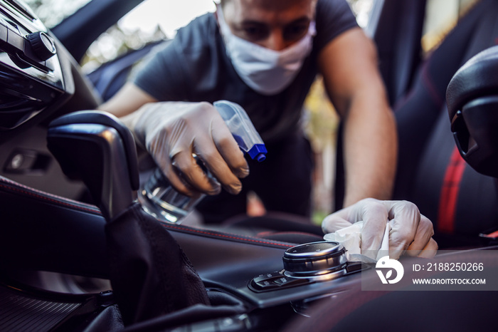 Man in protective suit with mask disinfecting inside car, wipe clean surfaces that are frequently touched, prevent infection of -covid 19 virus ,contamination of germs or bacteria. Infection.