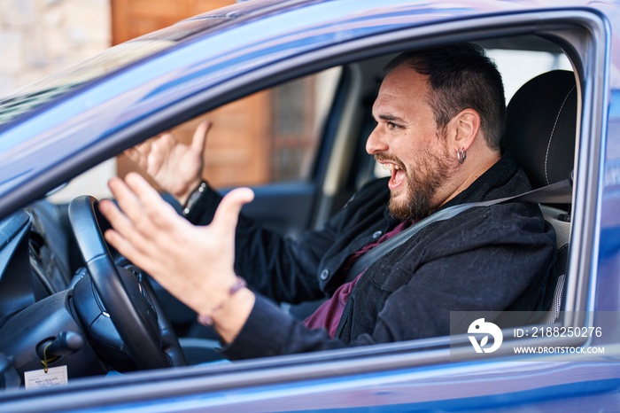 Young hispanic man driving car with furious expression at street