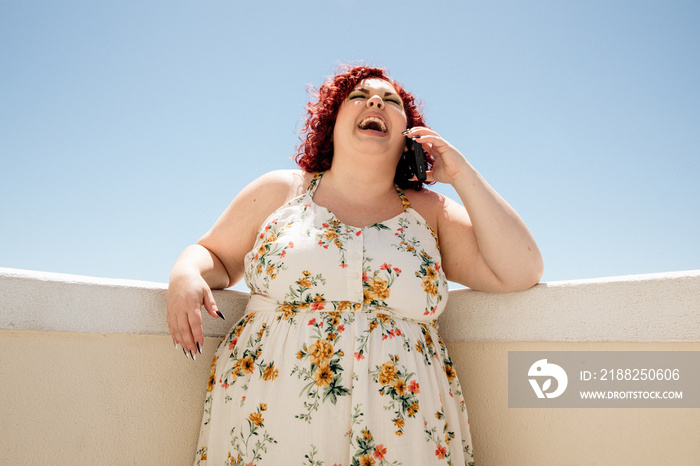 plus size woman laughs while on phone outside