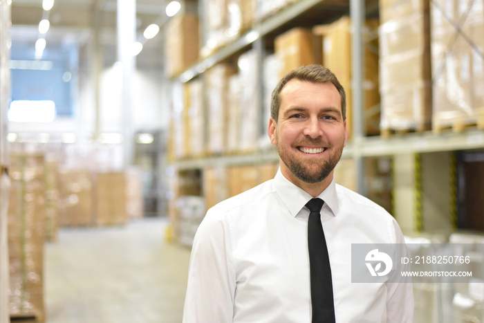 portrait friendly businessman/ manager in suit working in the warehouse of a company