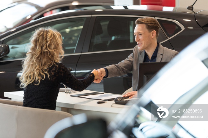 Smiling salesman doing handshake with female customer