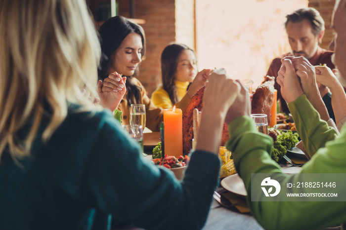 Photo of big family prayer tradition hold hands thanks giving dinner holiday sit served table turkey living room indoors