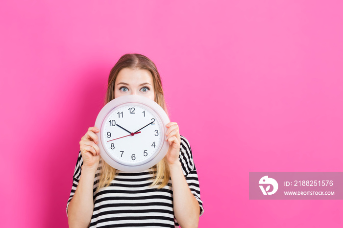 Young woman holding a clock