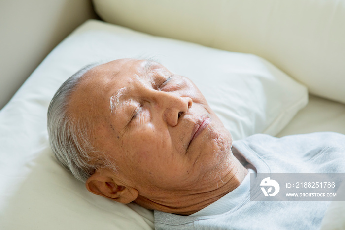 Elderly man resting in bed with eyes closed