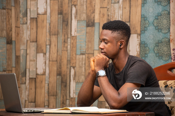 black teenager receiving lectures online, focused and listening while looking at his laptop computer