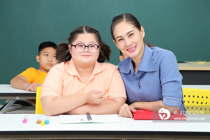 Asian disabled children Or, an autistic child learns to read, write and train their hand and finger muscles with a teacher at their classroom desk.