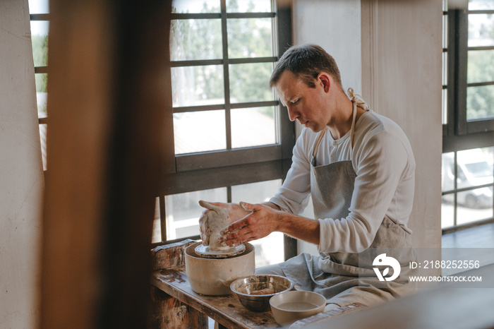 Young man working with clay on potter’s wheel