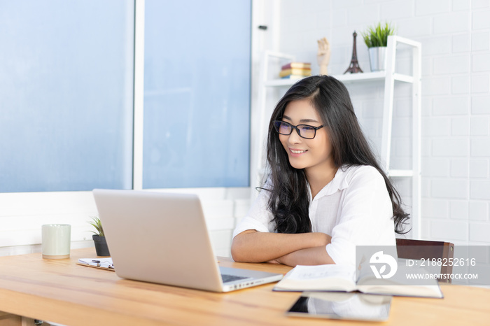 Education study abroad,Asian student girl wear glasses table looking book while do homework with laptop making video call abroad using internet friend connection, happy mood smiling broadly in library