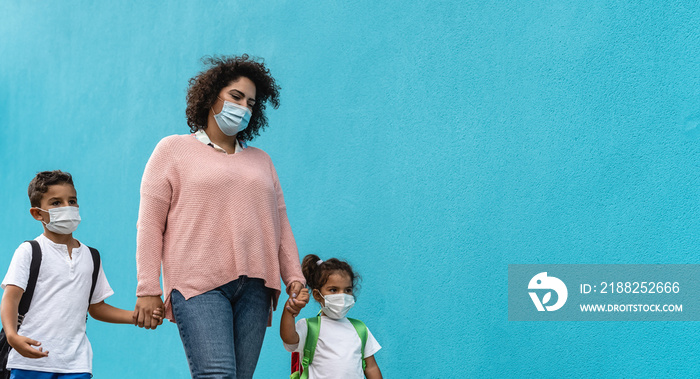 Mother with son and daughter wearing face protective mask going back to school during corona virus pandemic - Healthcare and education concept