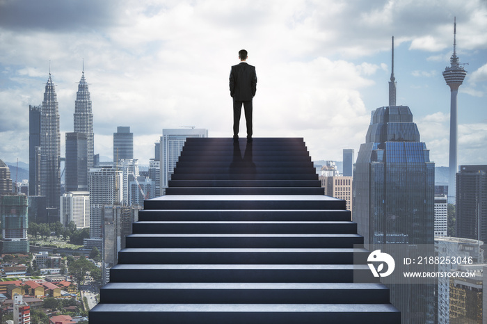 Back view of man standing on stairs on blurry city background. Success and growth concept.