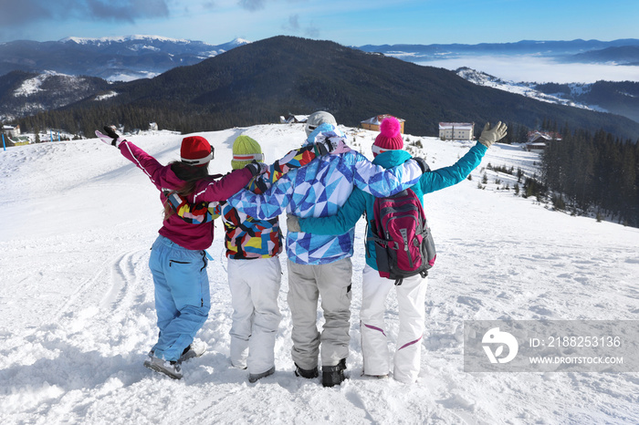 Happy friends on ski piste at snowy resort. Winter vacation