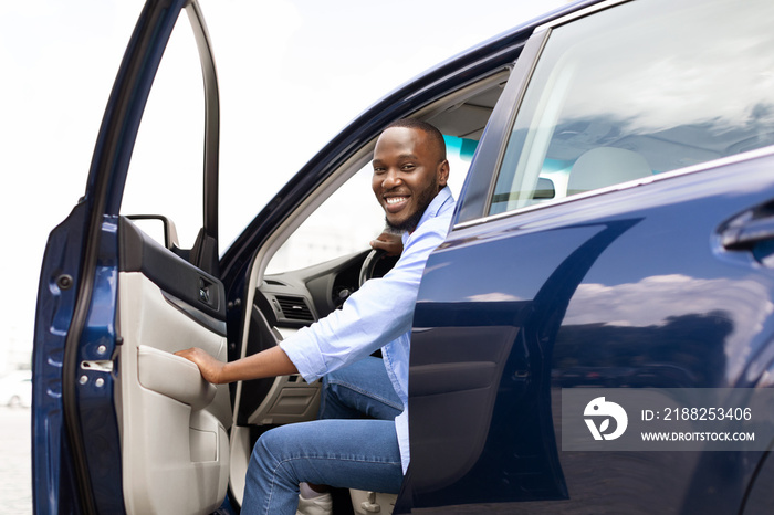 Smiling black man driving new car in the city