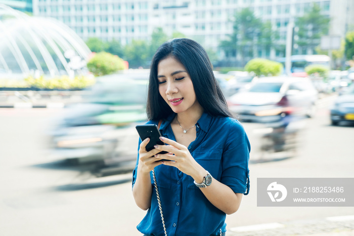 Asian woman using a phone on the roadside