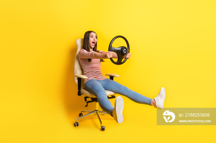 Full length body size view of pretty cheerful girl sitting holding steering wheel fooling having fun isolated over bright yellow color background