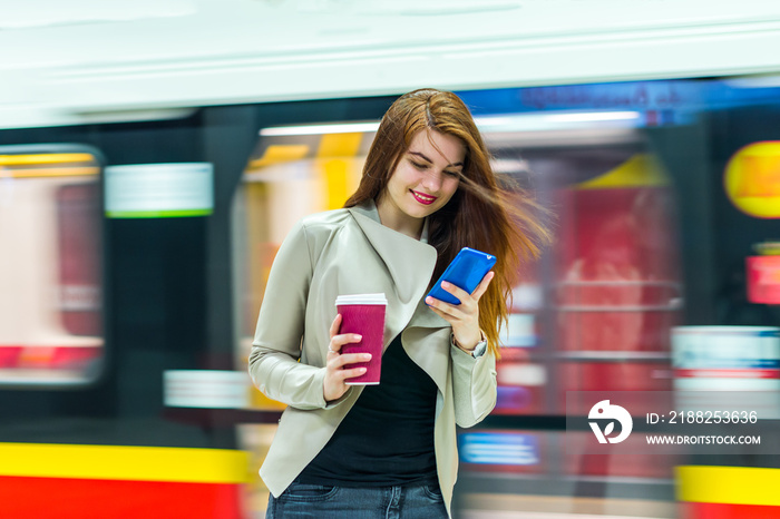 The girl near subway train looking at the smartphone