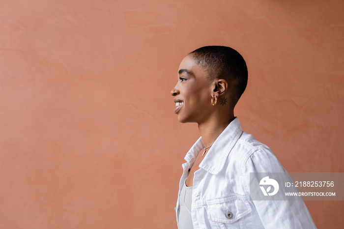 Side view of smiling short haired african american woman standing near wall outdoors.