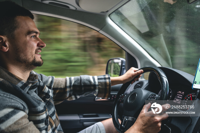 A man driving a car rides in a mountainous forest area.