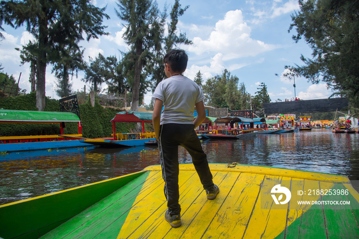 niño de pie sobre lancha trajinera en xochimilco mexico