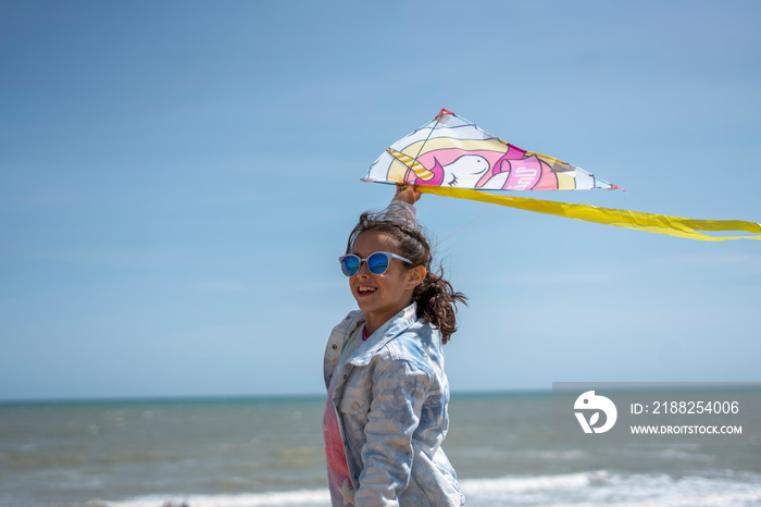 Girl (8-9) flying kite on beach