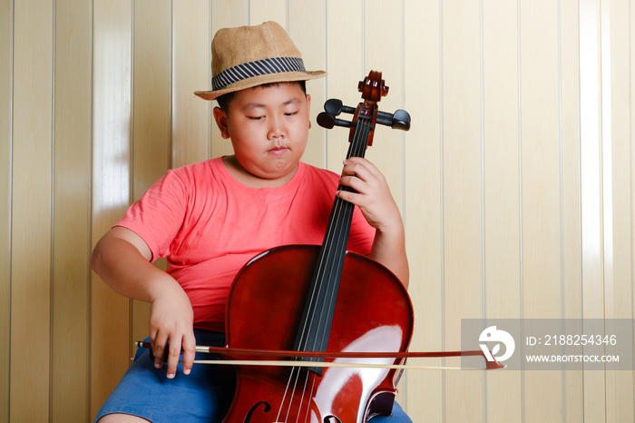 Asian boy playing a classical instrument cello at his house