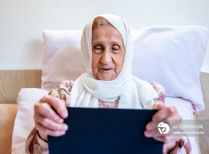 Portrait of senior Arabic woman using electronic tablet at home