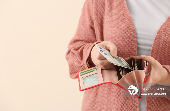 Senior woman with wallet on color background, closeup