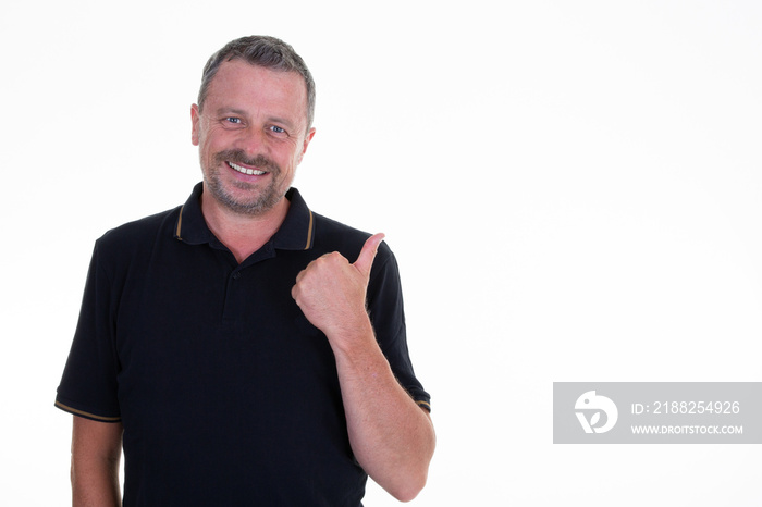 middle aged businessman wearing black polo standing over isolated white background smiling with happy face looking and pointing to the side with thumb up