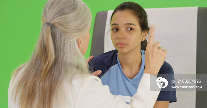 An elderly medical professional tests an injured soccer player on green screen