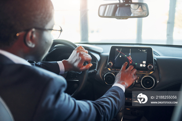 Vehicle interior. Young african american businessman in black suit is in the automobile