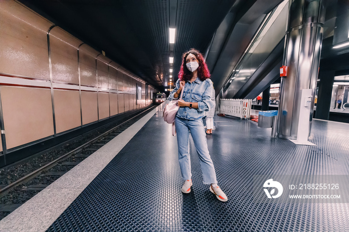 A girl in a protective medical mask waits for her train in the subway during the outbreak of the coronavirus pandemic