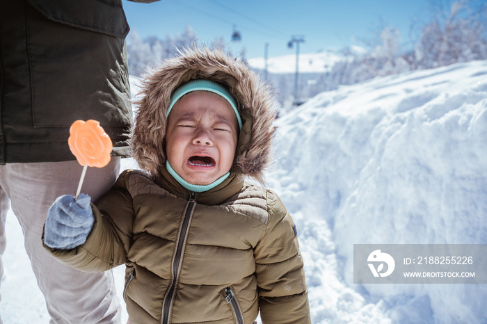 close up of boy crying outloud while standing outside in the snow wearing hoodie