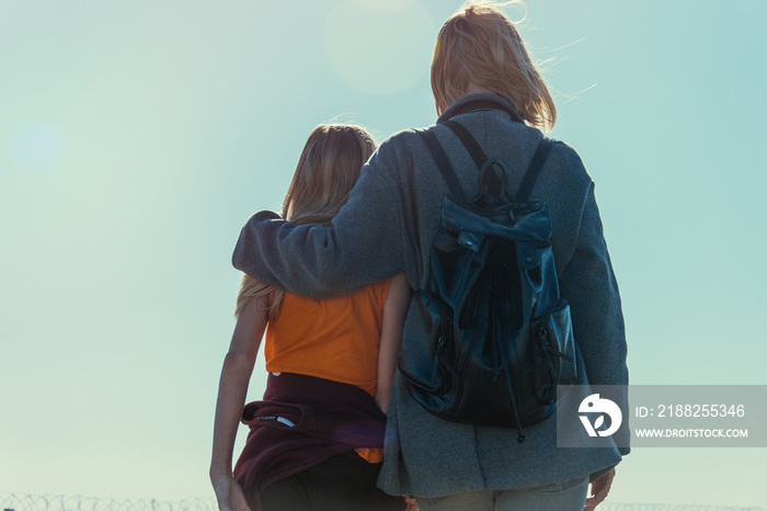 Mutual understanding between the parent and the child. Mother and daughter teenager stand embracing against the sky.