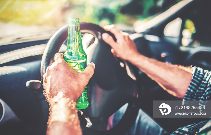 A man drinks beer while driving a car. Dangerous driving