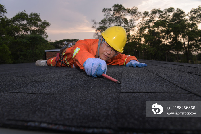 Roofer worker in special protective work wear and gloves,repairing the roof of a home, A worker replaces shingles on the roof of a home