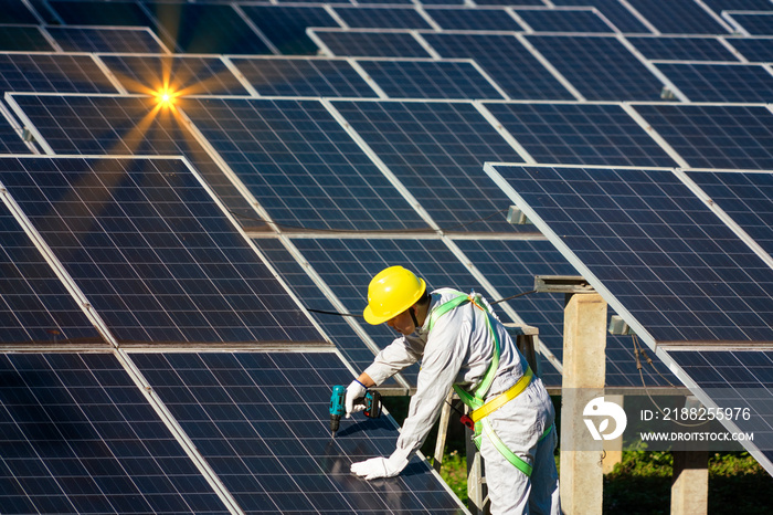 Male technician wearing protective clothing for safety climbs to install solar panel at solar farm using sunlight as electricity.Renewable Energy and Electricity Concept