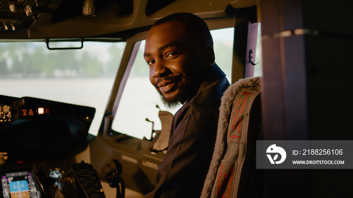 Portrait of african american copilot sitting in airplane cockpit with captain, ready to fly airline plane with control panel dashboard. Navigation command with power engine in cabin.