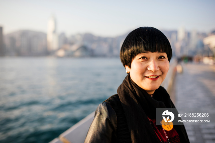 Portrait of mid adult woman with short hair in front of water looking at camera smiling